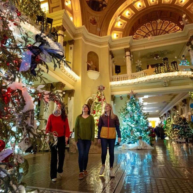 Three women admire colorfully decorated trees at Christmas at the Capitol in Pierre, South Dakota.