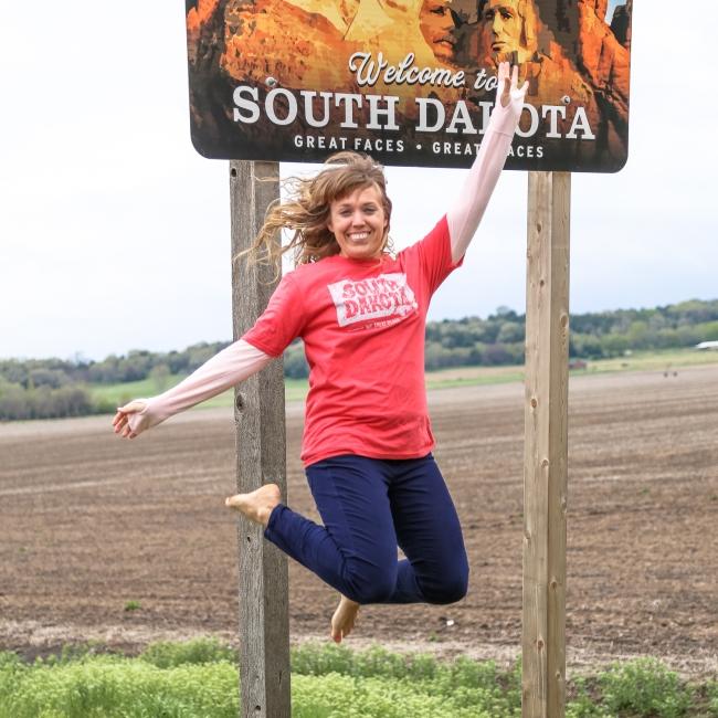 Jumping in front of the Welcome to South Dakota sign