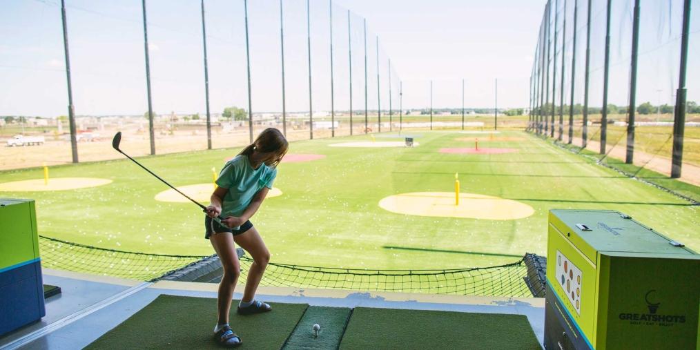 Young teen girl swinging a golf club at Great Shots