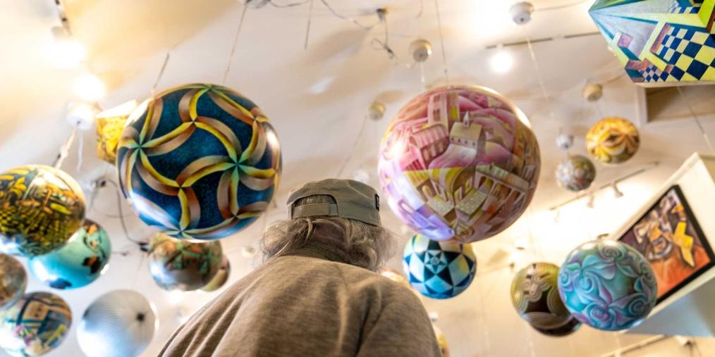 Man looking up at spherical artwork hanging from a gallery ceiling