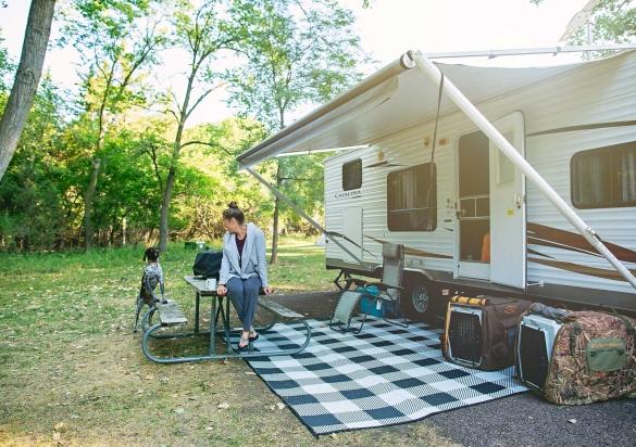 Woman sitting on picnic table in front of a camper