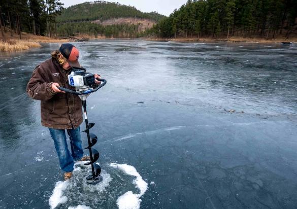 Angler drilling hole in the ice in the Black Hills