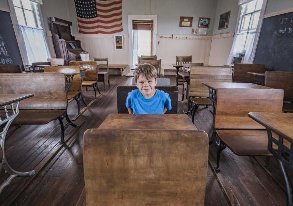 Boy sitting at a desk inside the Laura Ingalls Wilder Schoolhouse