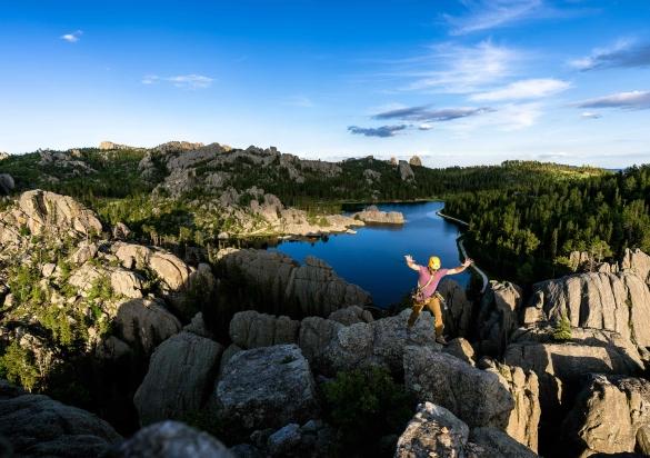 A rock climber jumping across the granite formations near Sylvan Lake in Custer State Park.