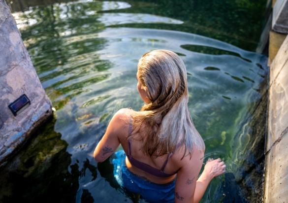 Woman entering into mineral waters in outdoor pool at Moccasin Springs Natural Mineral Spa in Hot Springs, South Dakota.