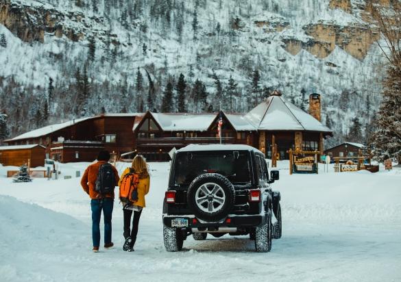 A couple walking away from their Jeep towards Spearfish Canyon Lodge Resort tucked in the snow-covered Black Hills National Forest.