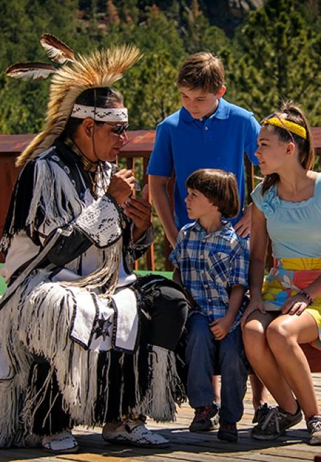 Native American Tribal dancer talking with tourist family