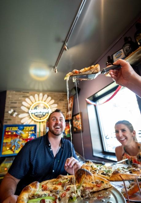 A couple enjoys the sight of a cheesy piece of pizza being served at Danger Von Dempsey's in Aberdeen