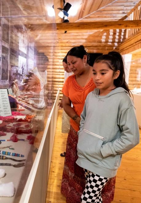 Two people look upon a collection of Native American crafts