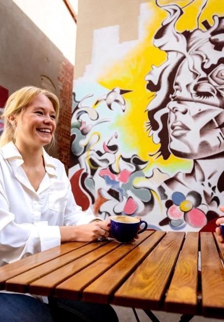 A person enjoys coffee in front of art in the patio area of M.B. Haskett Delicatessen in Sioux Falls