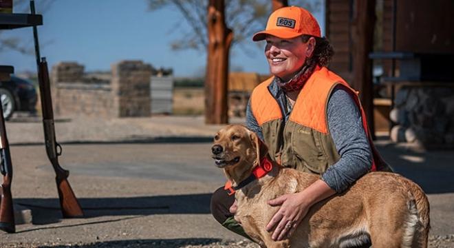 Woman hunter kneeling with a hunting dog